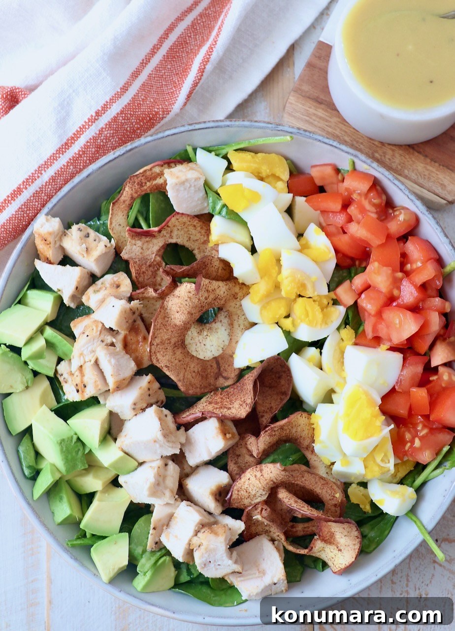 cobb salad in bowl with honey dijon dressing in bowl on the side