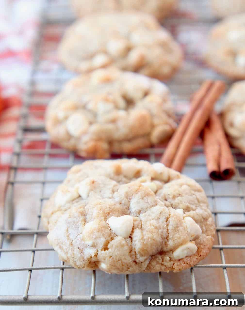 White chocolate chip cookies on wire baking rack with cinnamon sticks