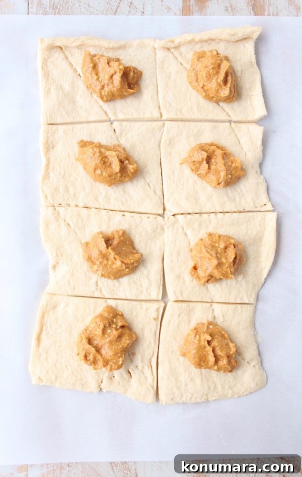 pumpkin cream cheese filling dolloped on crescent roll dough, cut into squares