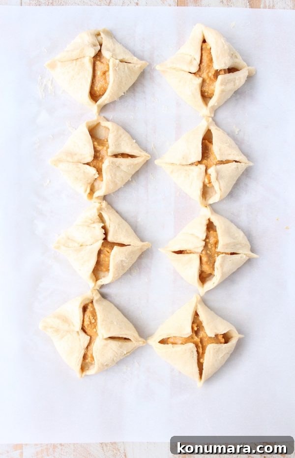 uncooked pumpkin filled pastries on parchment paper