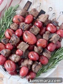 steak and potato kebabs stacked up on plate with rosemary sprigs