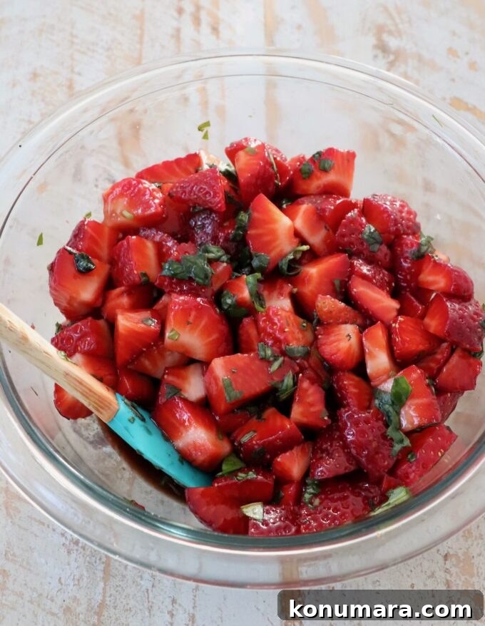 diced strawberries in a mixing bowl with balsamic vinegar and fresh basil
