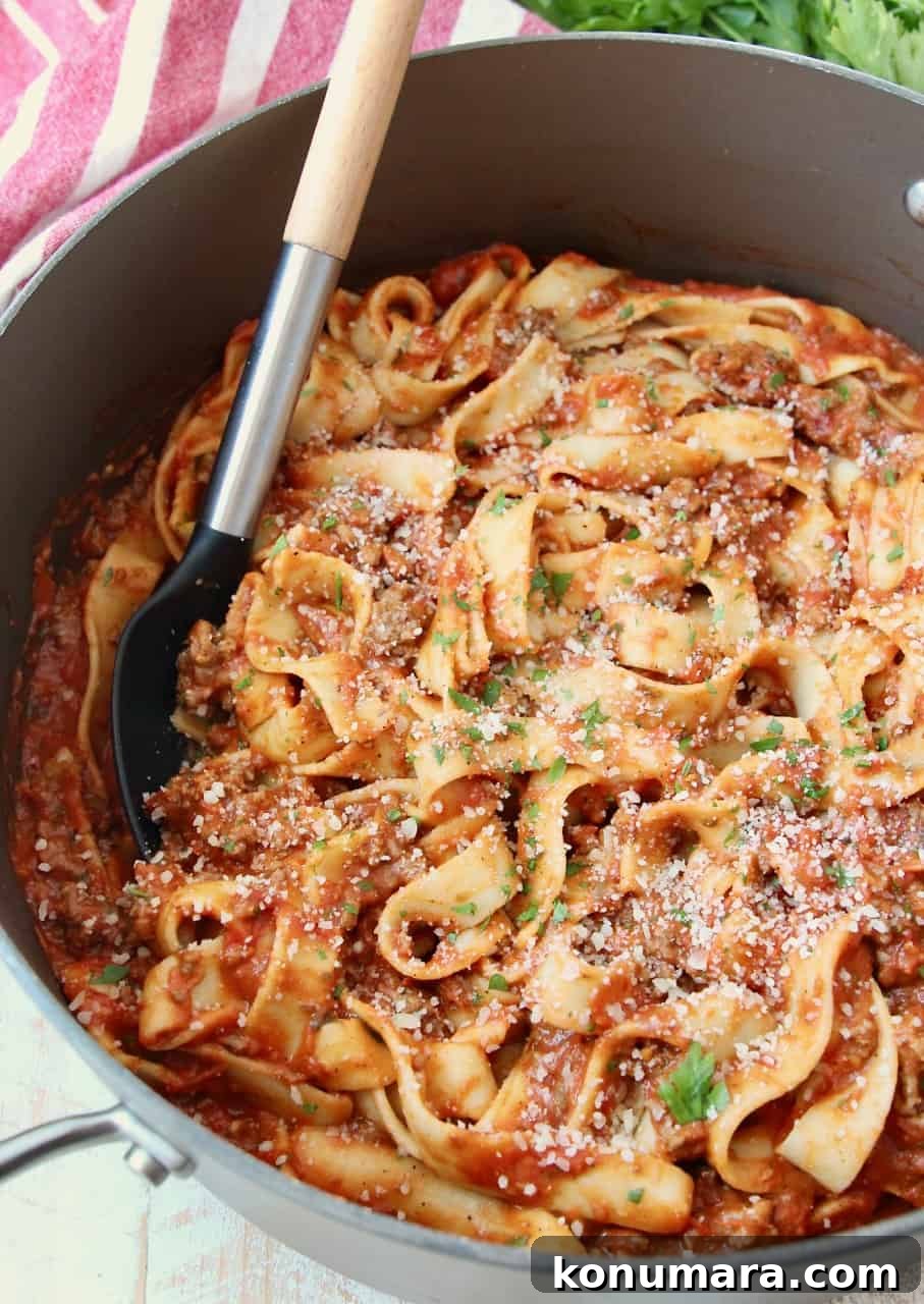 pasta tossed in tomato meat sauce in large pot with serving spoon