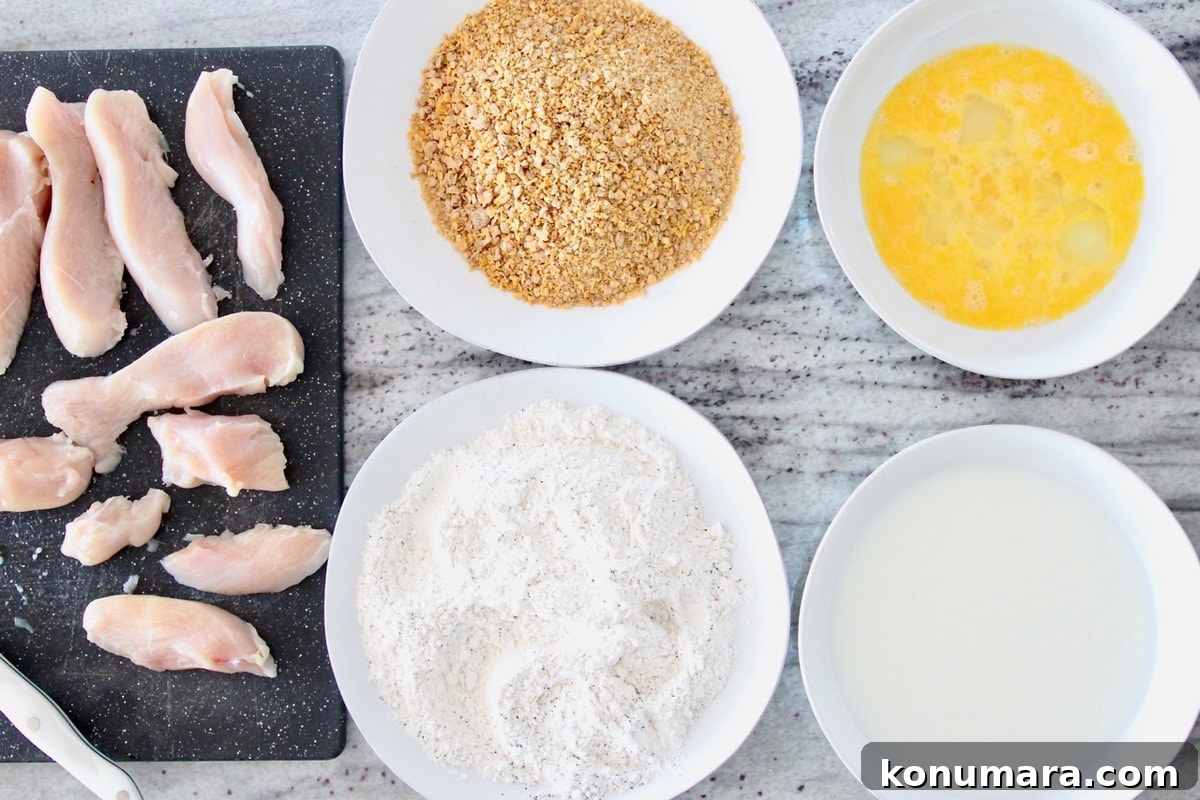 Honey Bunches of Oats Cereal-Crusted Chicken Strips Recipe 4 Chicken strip batter station with bowl of eggs, bowl of milk, plate of flour, plate of crushed cereal and raw chicken on cutting board