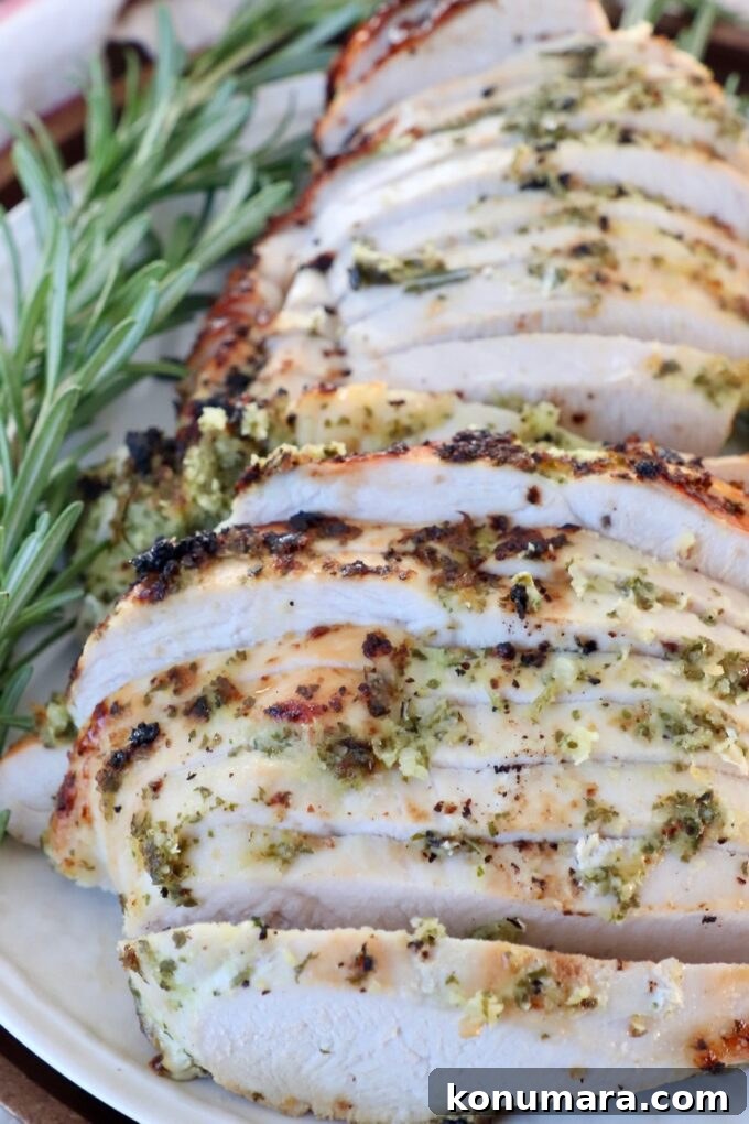 Herb-Rubbed Oven-Roasted Turkey Breast 2 sliced turkey on plate with fresh rosemary