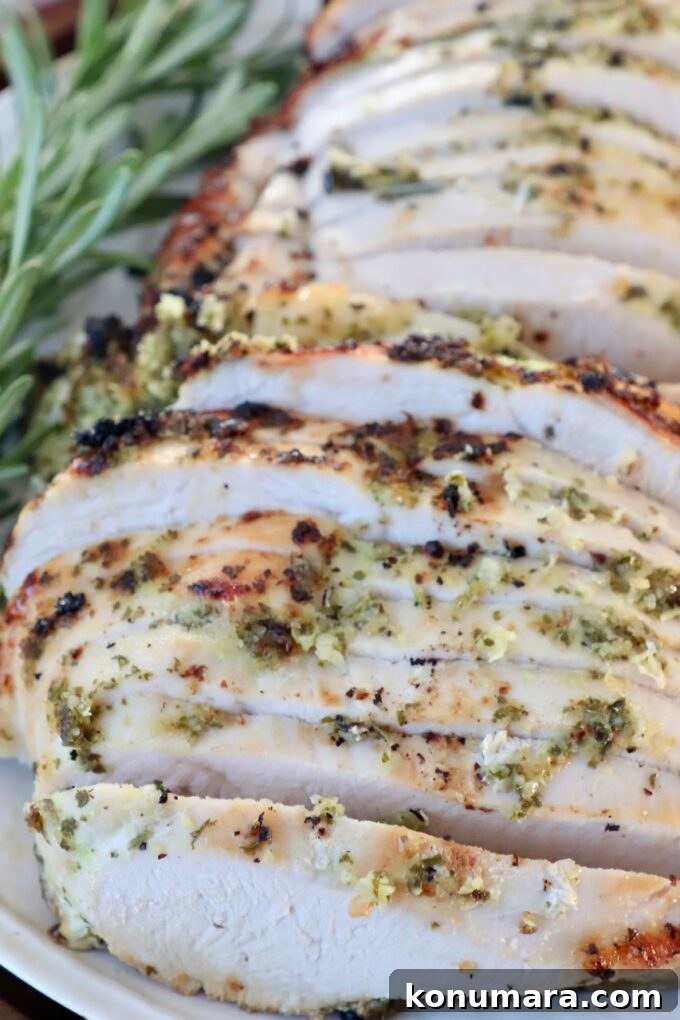 Herb-Rubbed Oven-Roasted Turkey Breast 6 slices of turkey on a plate with fresh herbs