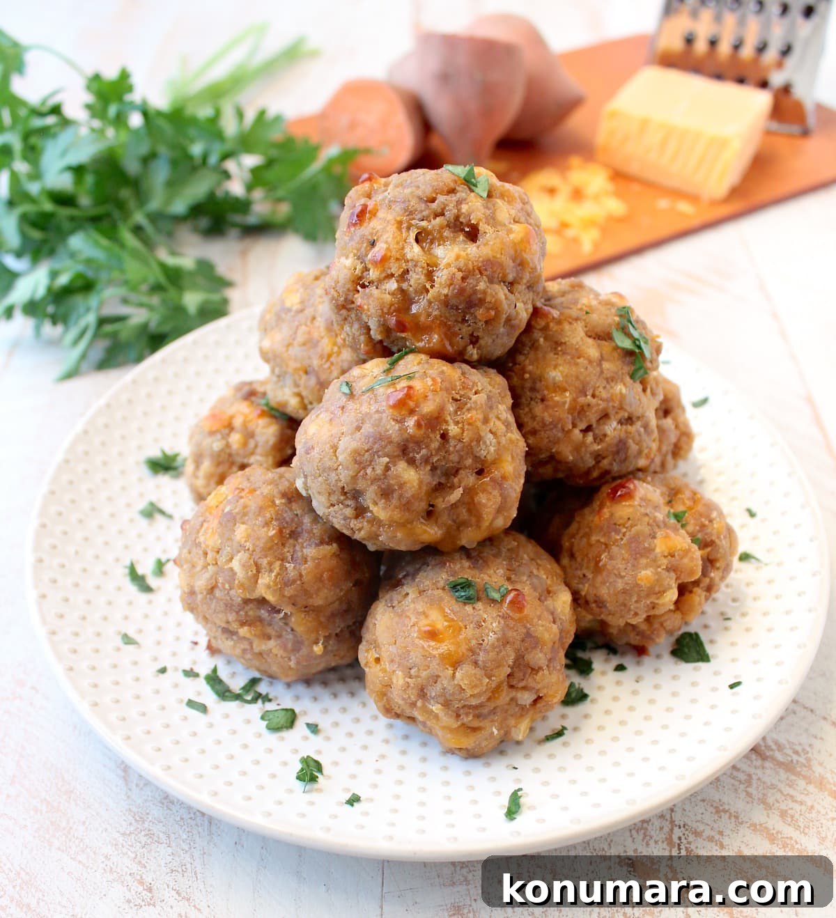 Gluten-Free Sweet Potato Sausage Balls Recipe 2 sweet potato sausage balls stacked on a white plate.