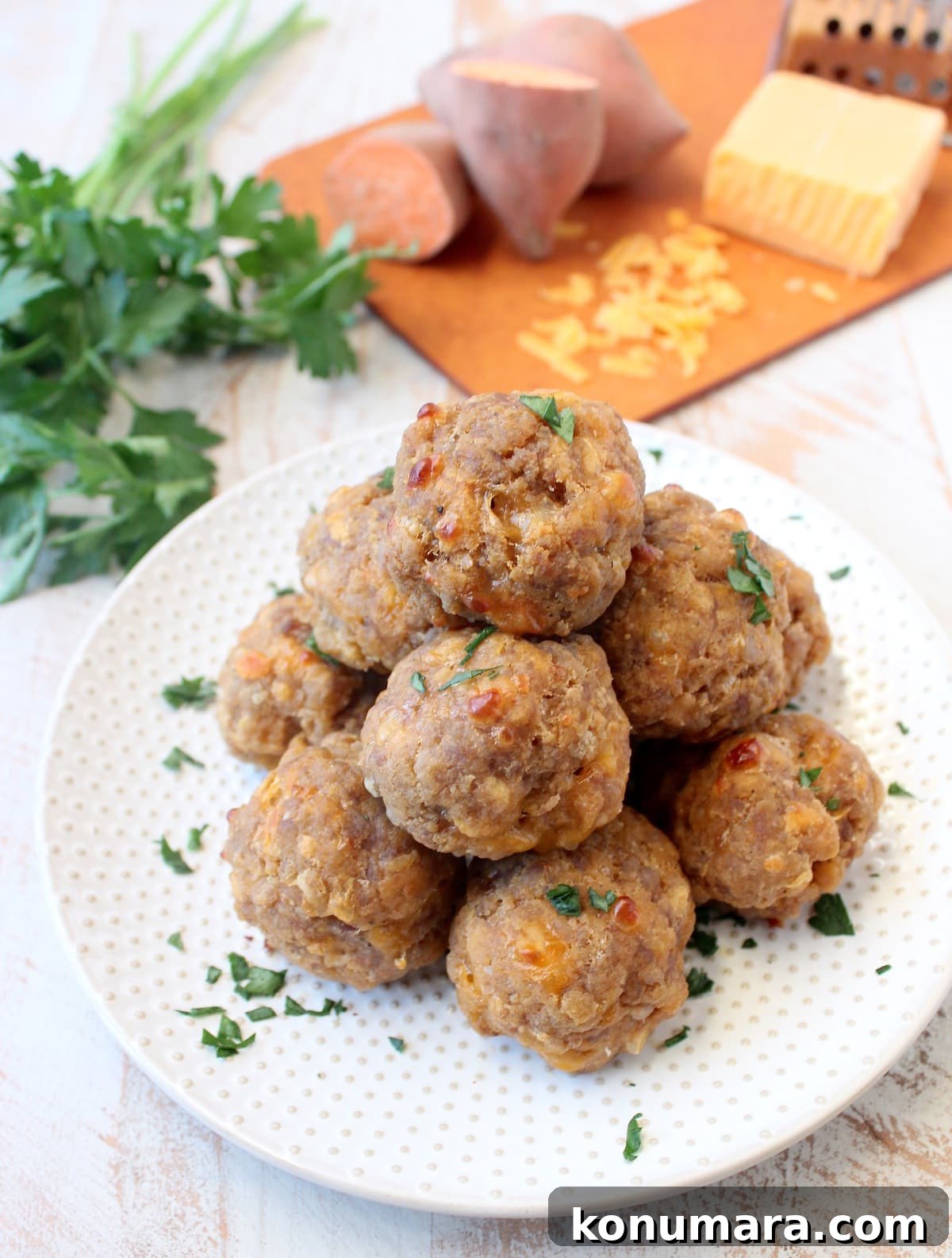 Gluten-Free Sweet Potato Sausage Balls Recipe 6 Sweet potato sausage balls on a white plate.