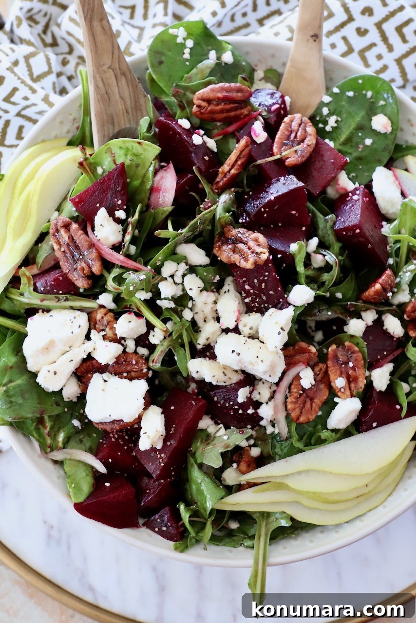 salad in bowl with serving spoons topped with roasted beets and feta