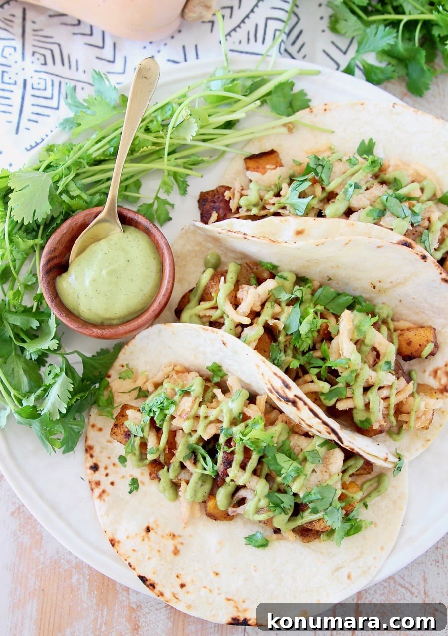 Roasted Butternut Squash Tacos with Avocado and Lime 3 Butternut squash tacos topped with crispy onions, avocado cream sauce and fresh cilantro on plate