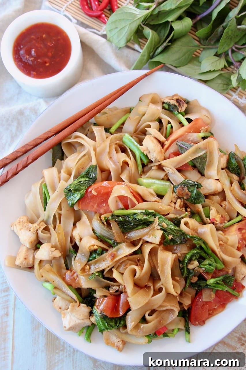 Authentic Thai Drunken Noodles (Pad Kee Mao) Recipe 2 Overhead shot of Drunken Noodles on white plate with brown chopsticks on the side