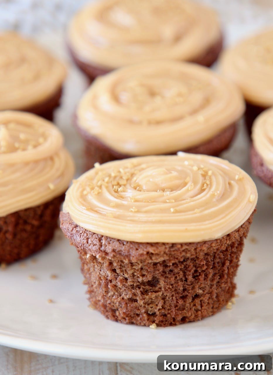 Gluten Free Peanut Butter Chocolate Cupcakes 2 chocolate cupcakes on plate with peanut butter frosting and gold sprinkles