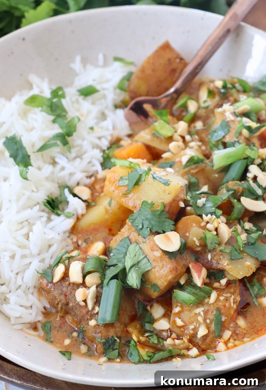 Slow Cooker Massaman Curry Chicken 8 chicken and vegetables in curry sauce in bowl with rice and fork