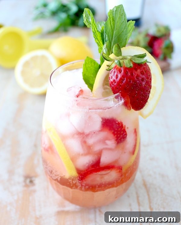lemon berry prosecco sangria in glass with strawberry, lemon and mint garnish on the side