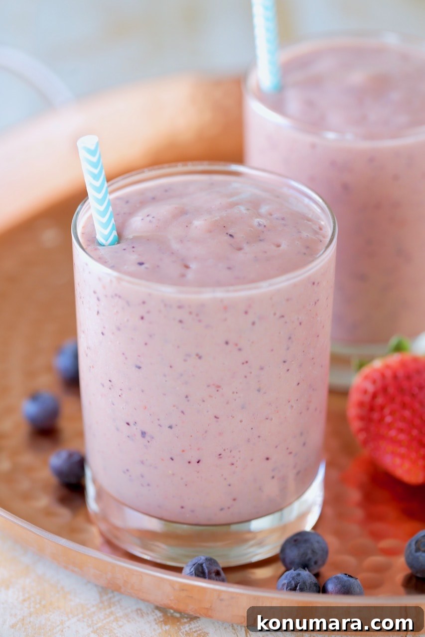 Fruit Smoothie for Heart Health 4 Fruit smoothie in glass with straw on copper tray with fresh strawberries and blueberries