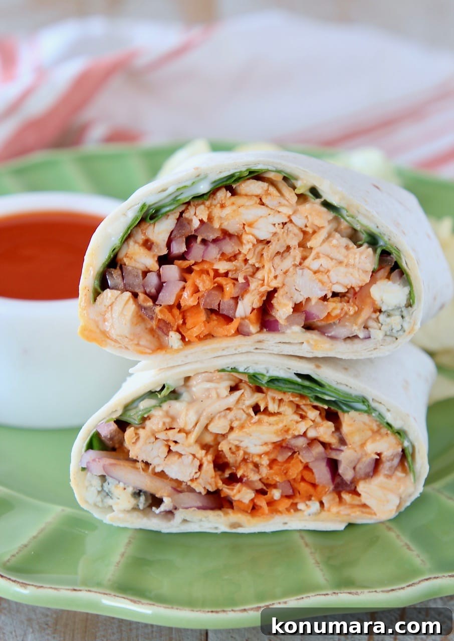 Buffalo chicken wrap sliced in half, sitting on top of each other on a green plate