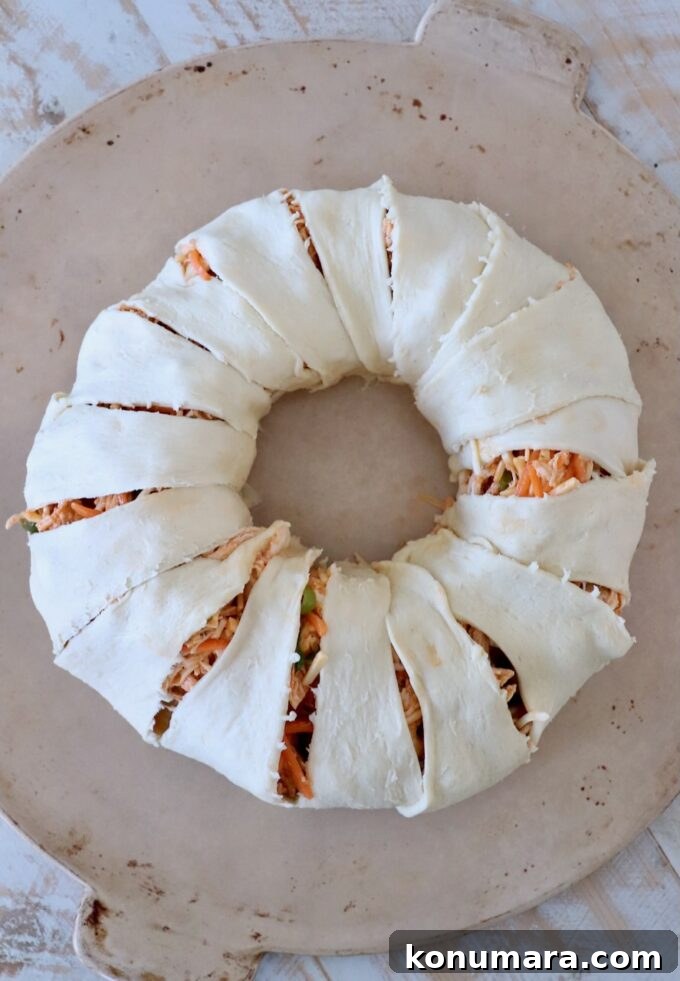 uncooked buffalo chicken pastry ring on round stone baking dish