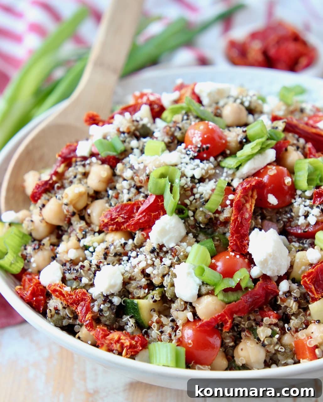 Quinoa salad in bowl with sun dried tomatoes, feta cheese and green onions