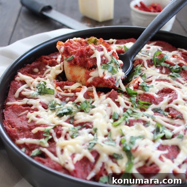 Mediterranean Sausage-Stuffed Shells Recipe 2 A black spoon scooping out a stuffed shell from a pot.