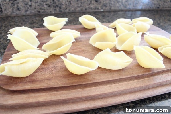 Mediterranean Sausage-Stuffed Shells Recipe 8 Cooked pasta shells on a wooden cutting board.