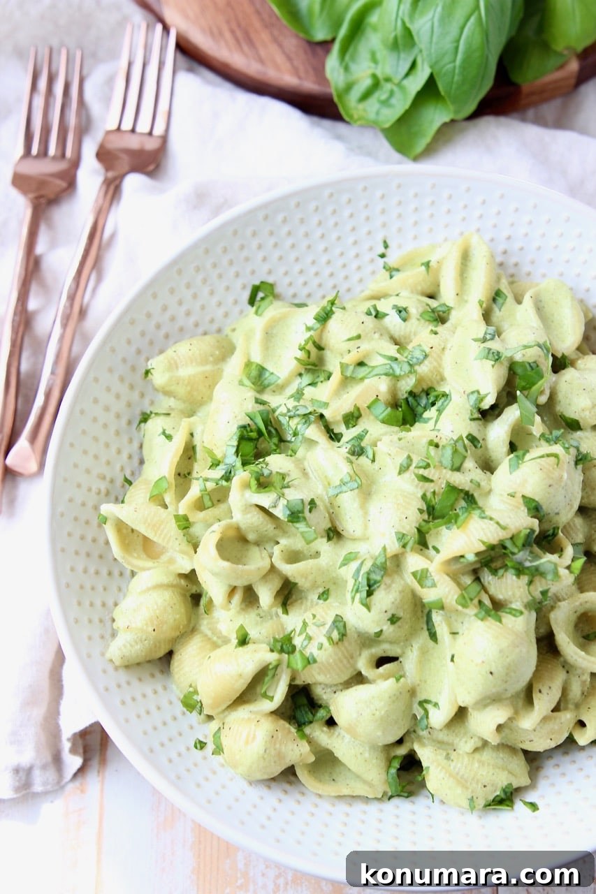 Cheesy Basil Pesto Pasta Recipe with Parmesan 4 Overhead shot of cheesy basil pesto pasta in white bowl with copper forks on the side