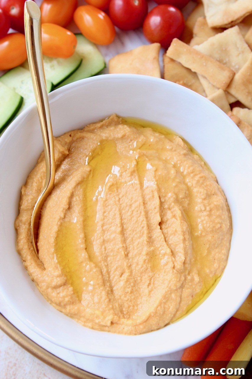 Spicy hummus in bowl with gold spoon