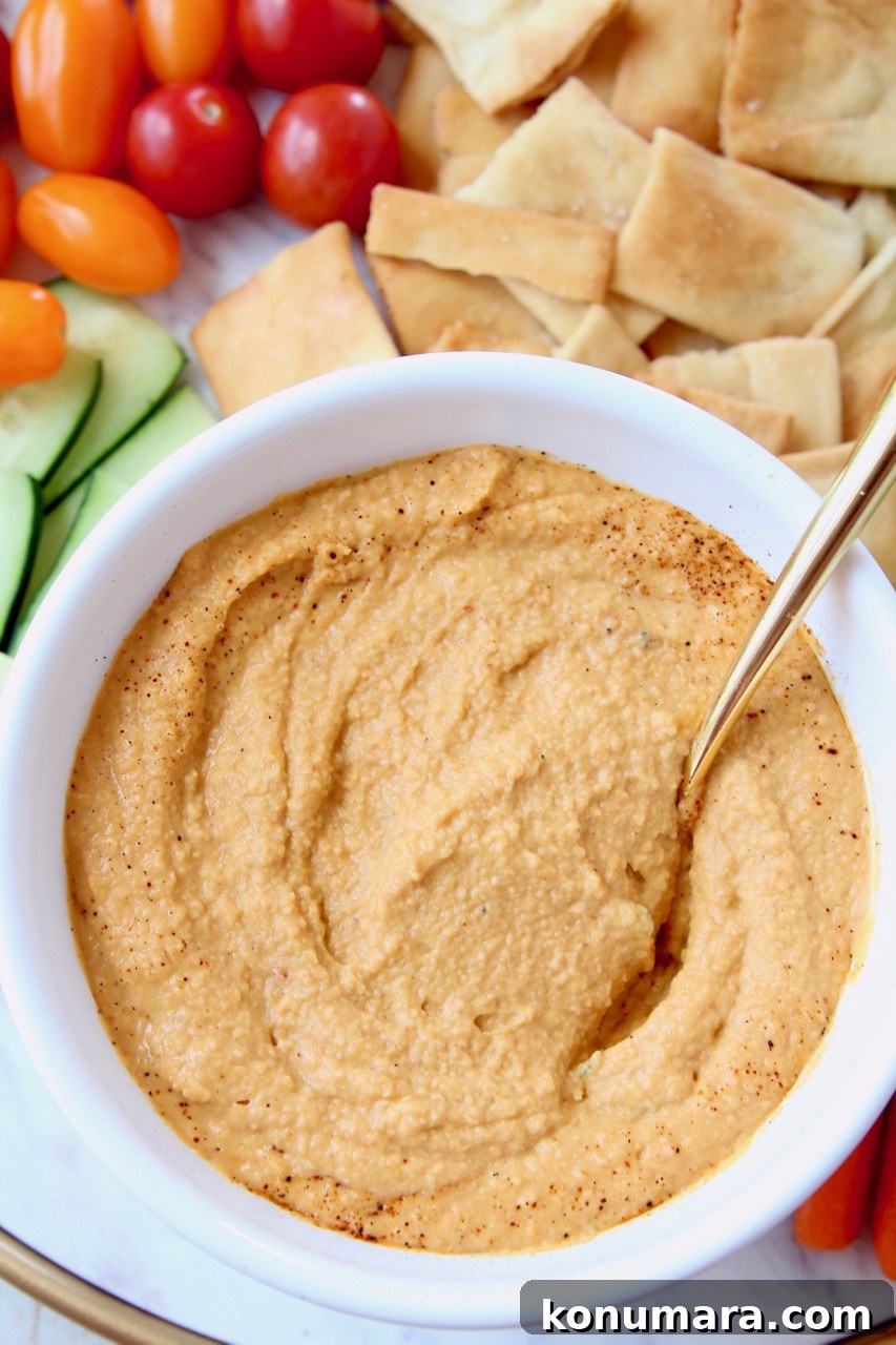 Spicy hummus in bowl with gold spoon