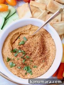 Spicy hummus in bowl topped with chopped cilantro and paprika