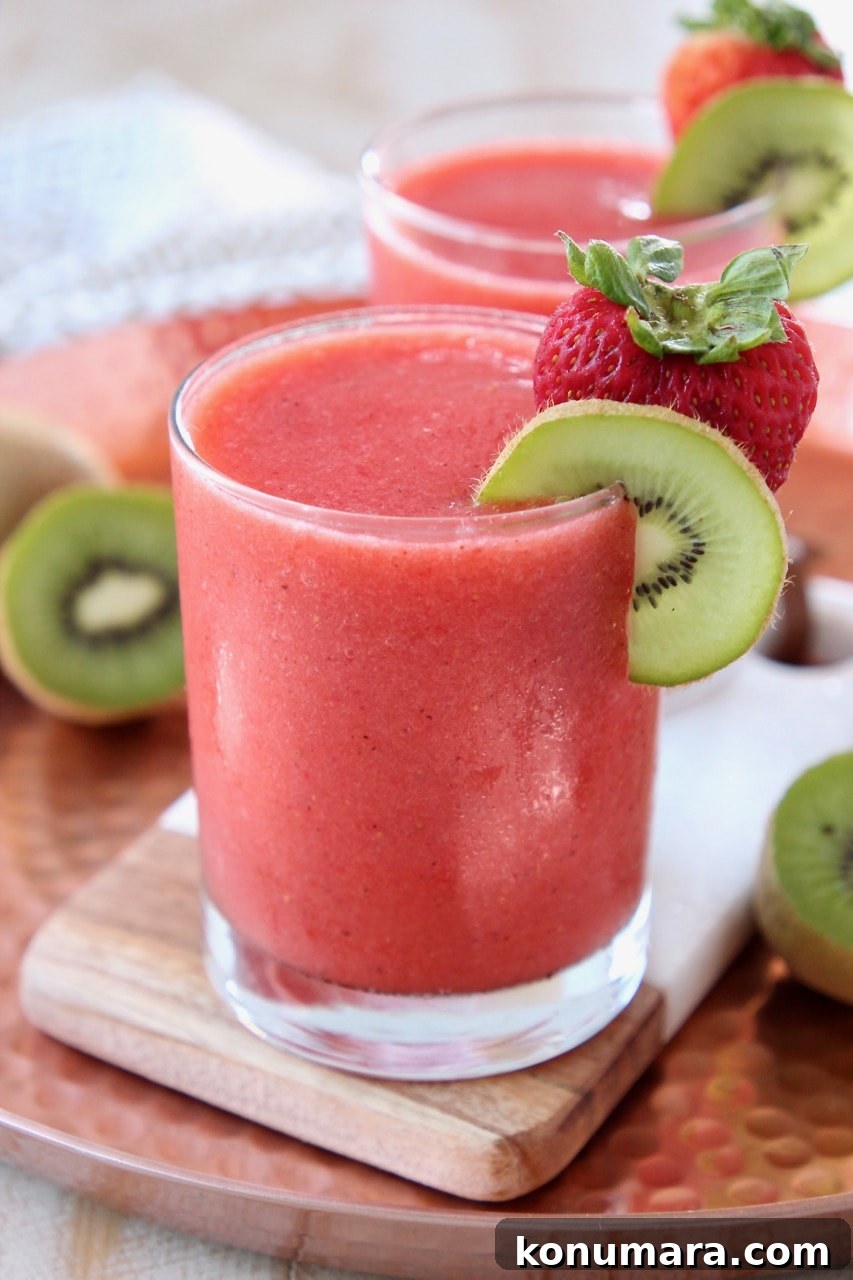 Strawberry Kiwi Slushie Recipe: Refreshing Summer Drink 2 Strawberry slushie in glass with strawberry and kiwi slice on the rim of the glass