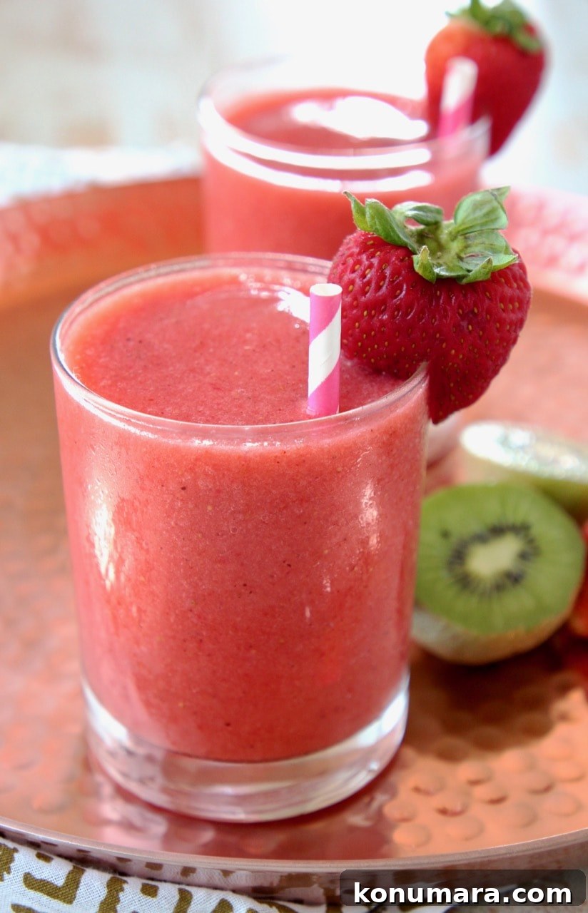 Strawberry Kiwi Slushie Recipe: Refreshing Summer Drink 3 Strawberry kiwi slush in glass with pink and white striped straw