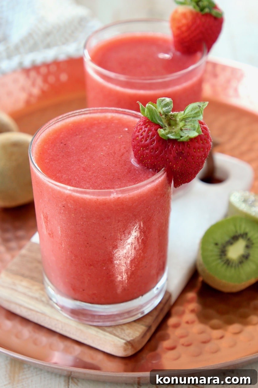 Strawberry Kiwi Slushie Recipe: Refreshing Summer Drink 4 Strawberry slushie in glass with strawberry and kiwi on the side