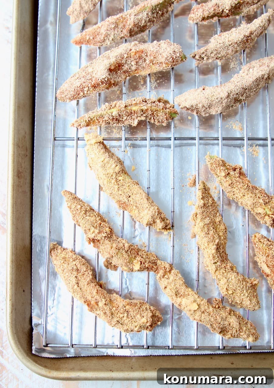 Breaded avocado slices on wire rack on baking sheet