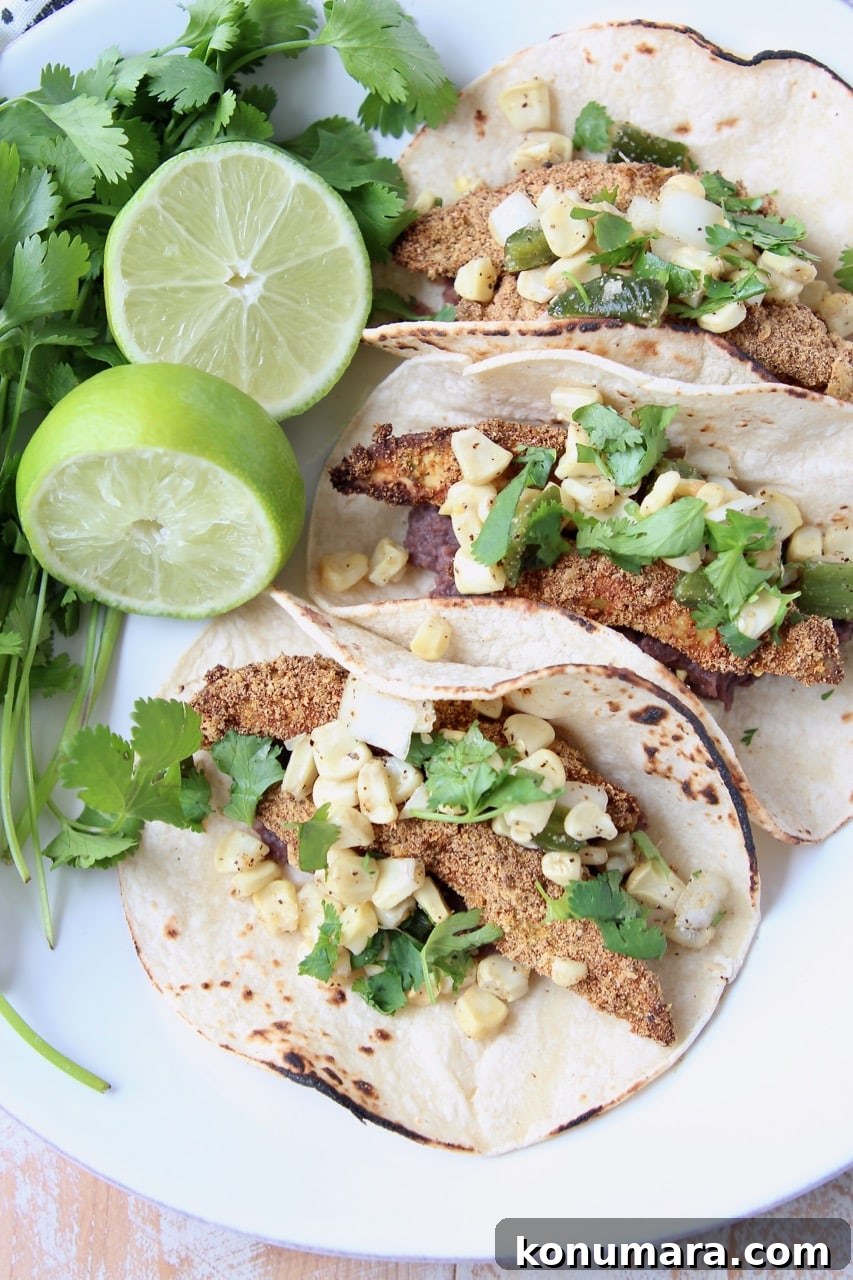 Overhead shot of crispy baked avocado tacos in corn tortillas on white plate with lime wedges