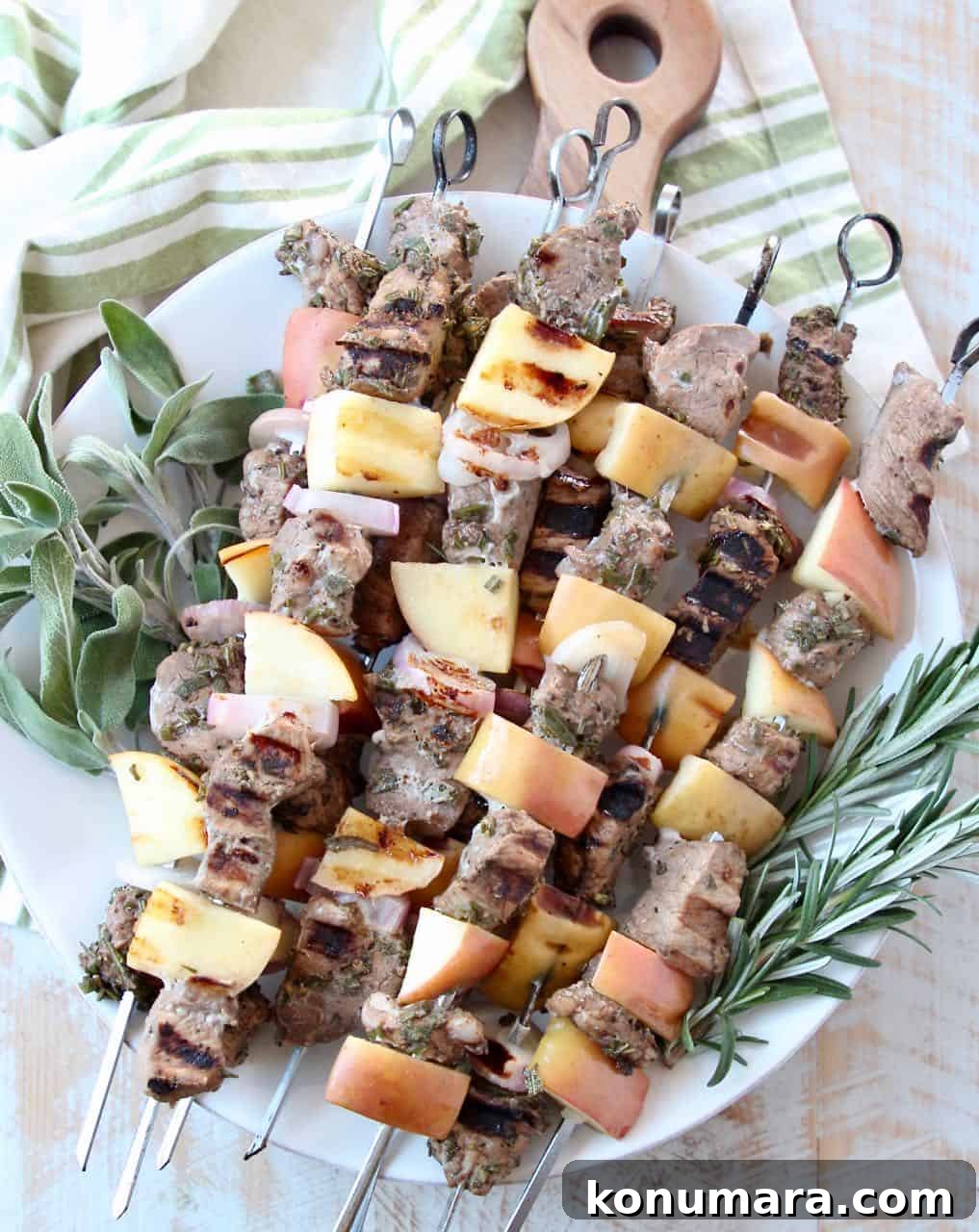 Pork skewers stacked up on plate with fresh herbs
