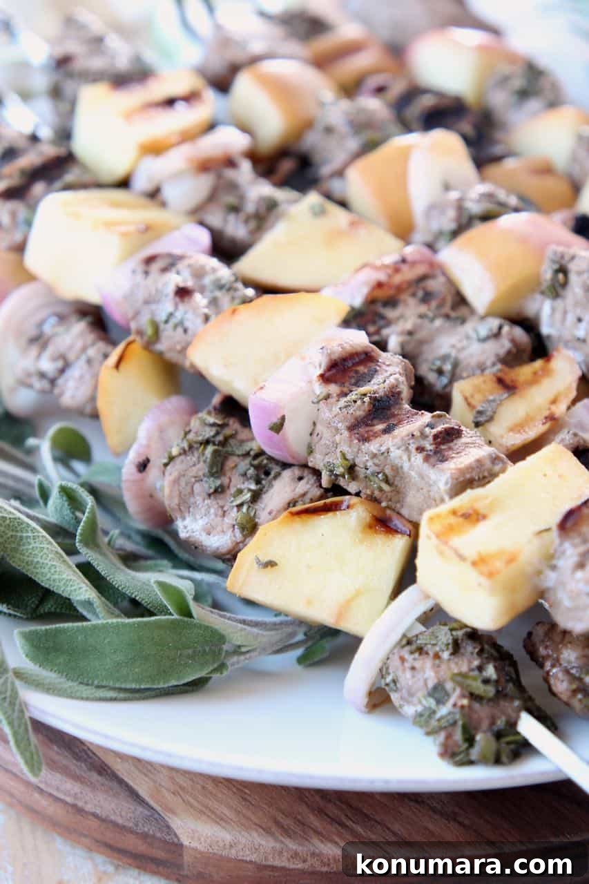 Pork and apple skewers on plate with fresh sage