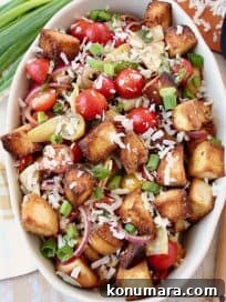Overhead shot of panzanella salad in large oval bowl topped with grated parmesan cheese