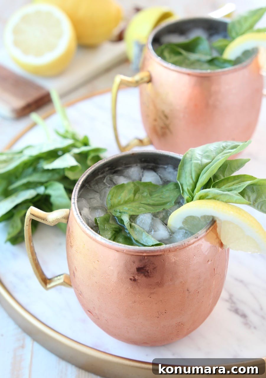 Peach and Basil Moscow Mule Cocktail Recipe 2 Moscow mule in copper mugs with fresh basil and lemon wedge on the side