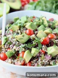 White bowl filled with quinoa salad with diced avocado and tomatoes