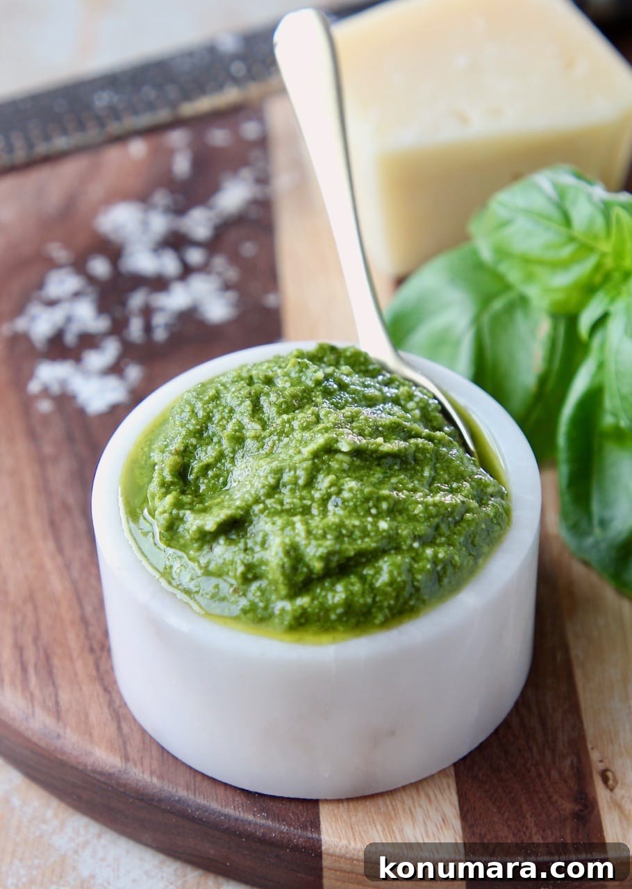 Basil pesto in white bowl on wood cutting board