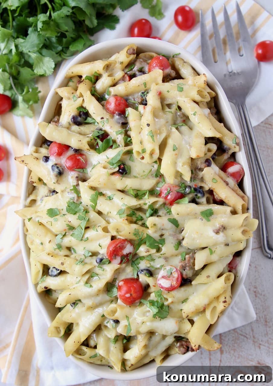 Taco pasta in a large oval casserole dish topped with cherry tomatoes and cilantro