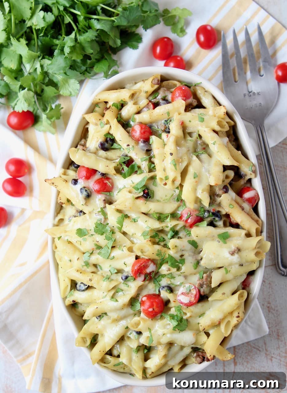 Taco pasta in large oval casserole dish with fork and cherry tomatoes on the side