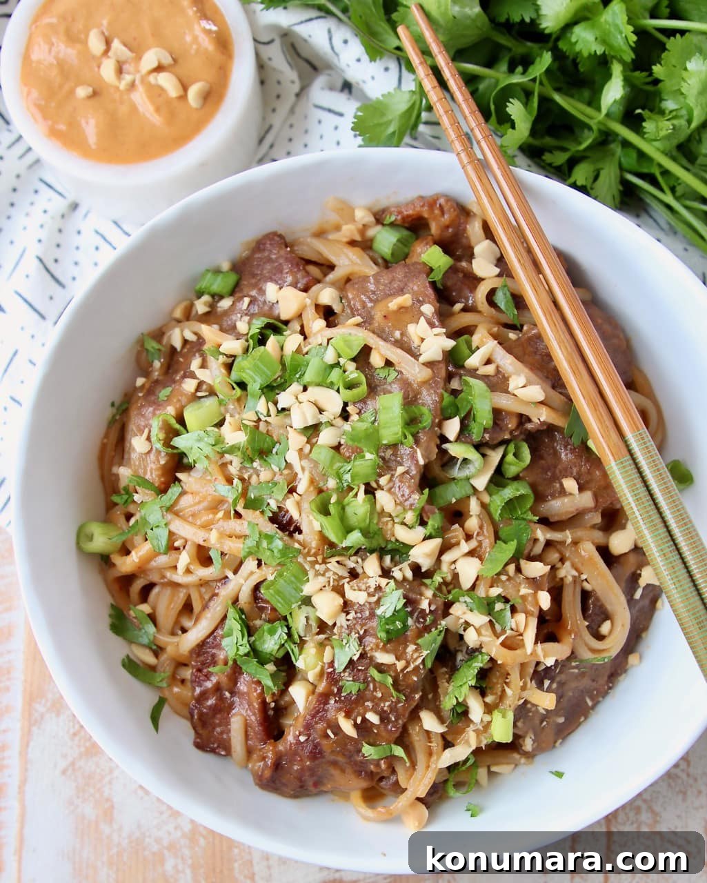 Authentic Thai Beef Noodle Bowl Recipe 2 Thai beef and noodles in white bowl, topped with diced green onions
