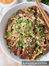 Authentic Thai Beef Noodle Bowl Recipe 5 Overhead shot of sliced beef and noodles in bowl with chopsticks on the side