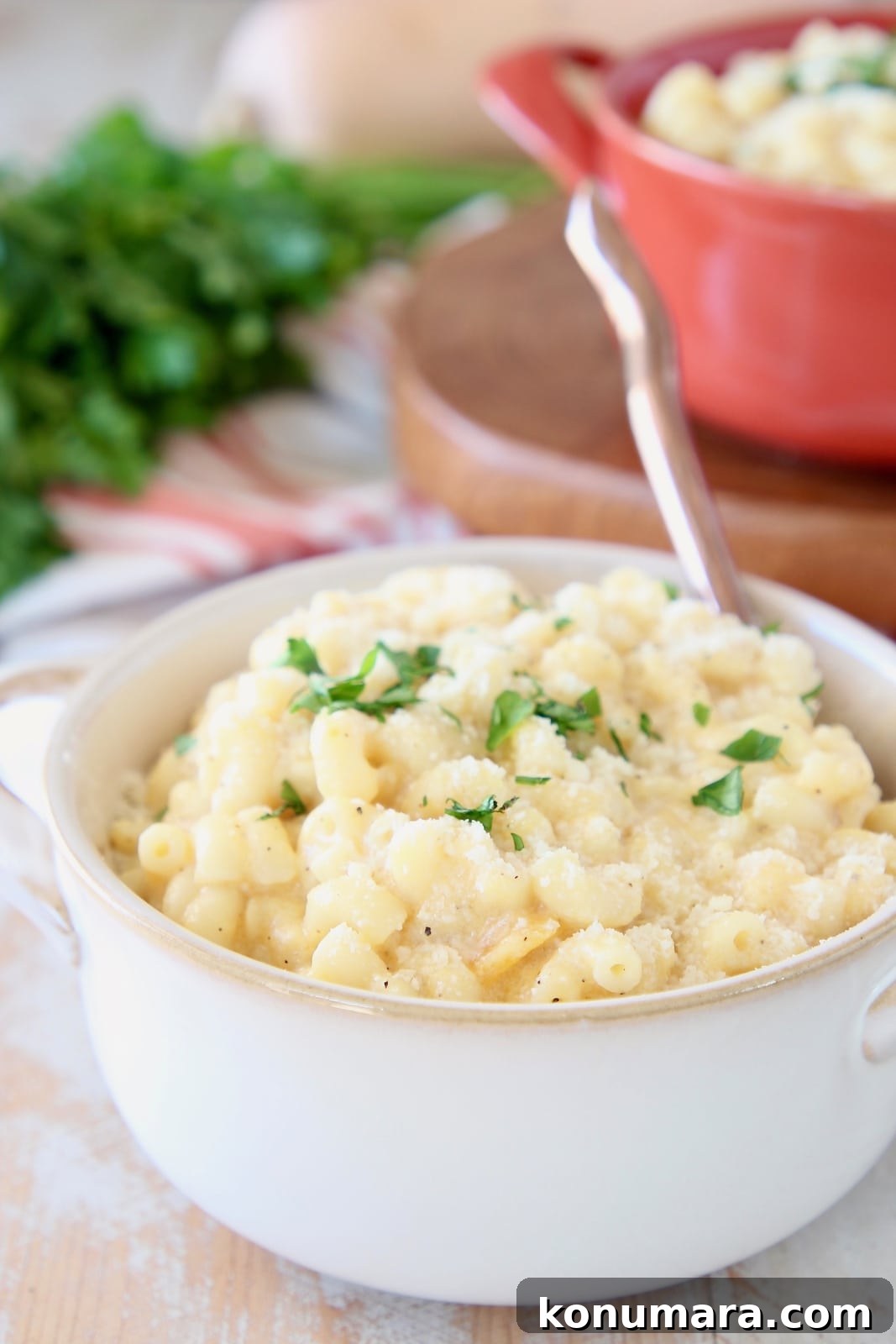 Butternut Squash Mac and Cheese in white crock with gold spoon and fresh chopped parsley
