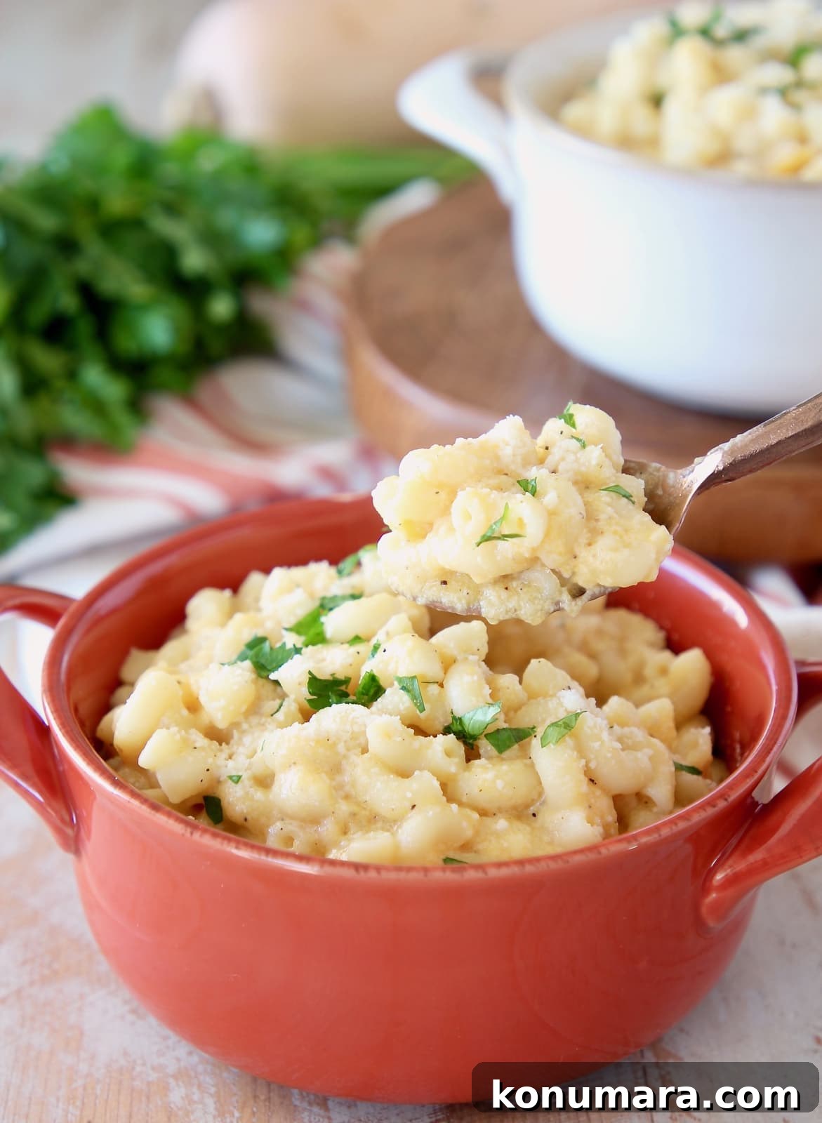 Butternut squash mac and cheese with spoonful taken out of orange crock