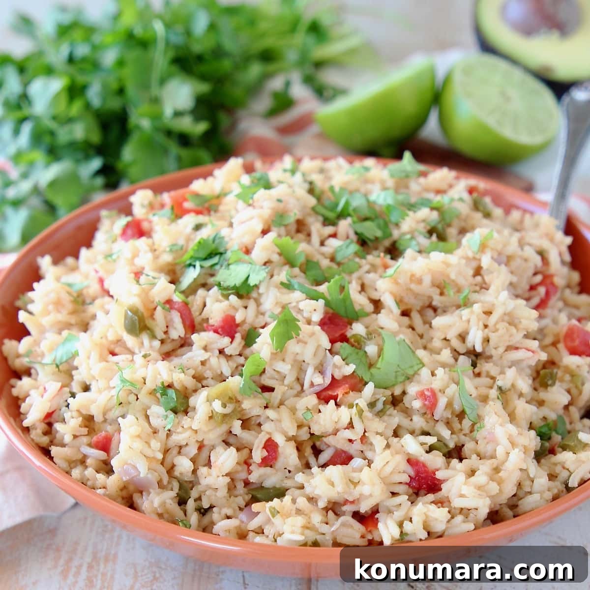 How to Make Authentic Mexican Rice (Arroz Rojo) 2 Mexican rice in orange bowl with cilantro and limes
