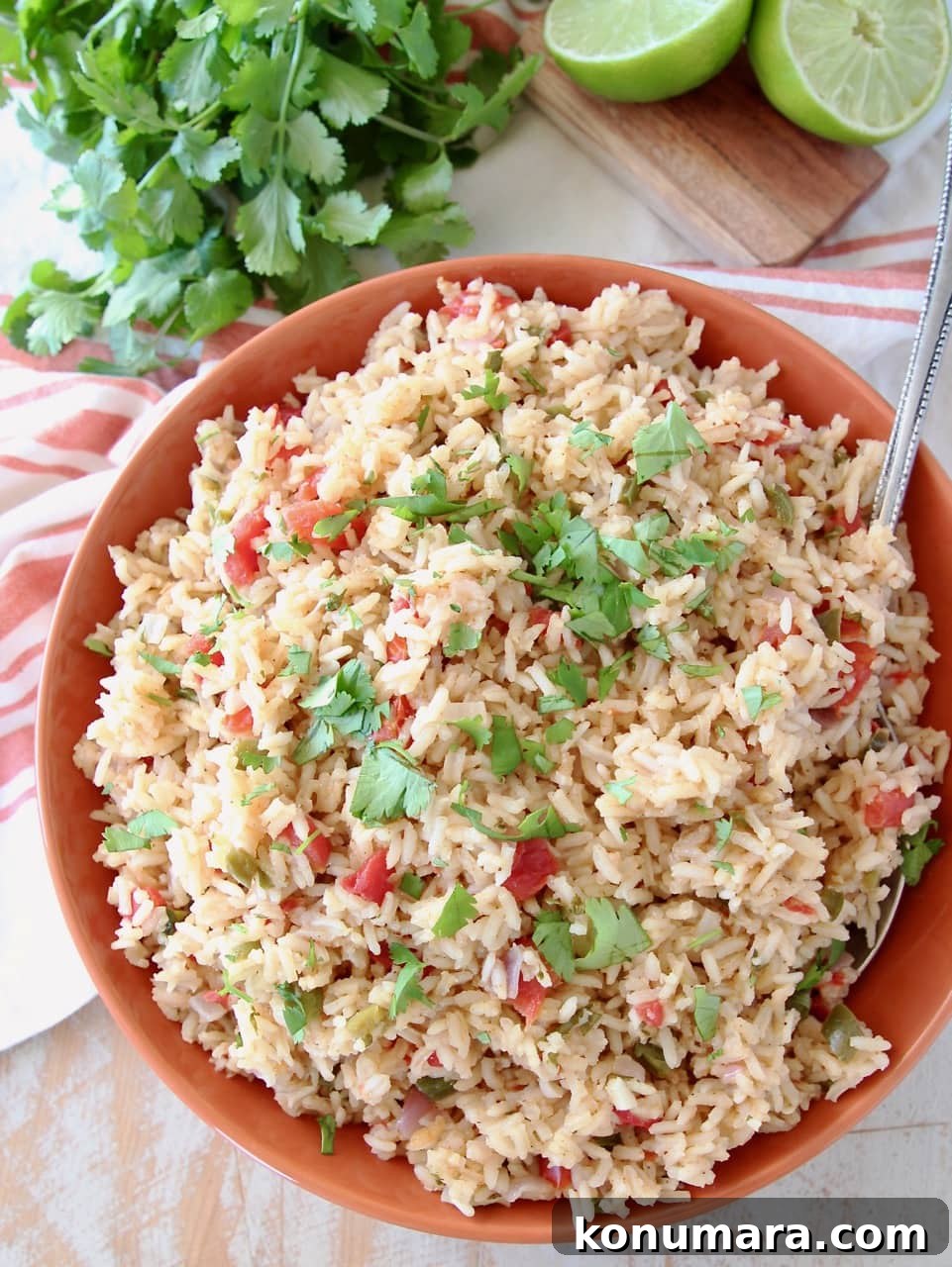 How to Make Authentic Mexican Rice (Arroz Rojo) 4 Mexican rice in orange bowl with serving spoon, topped with cilantro