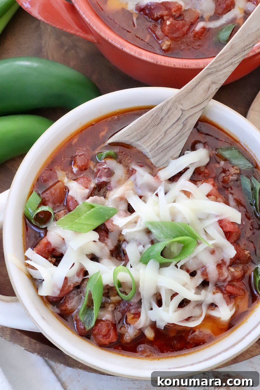 chili in a bowl topped with shredded cheese and diced green onions
