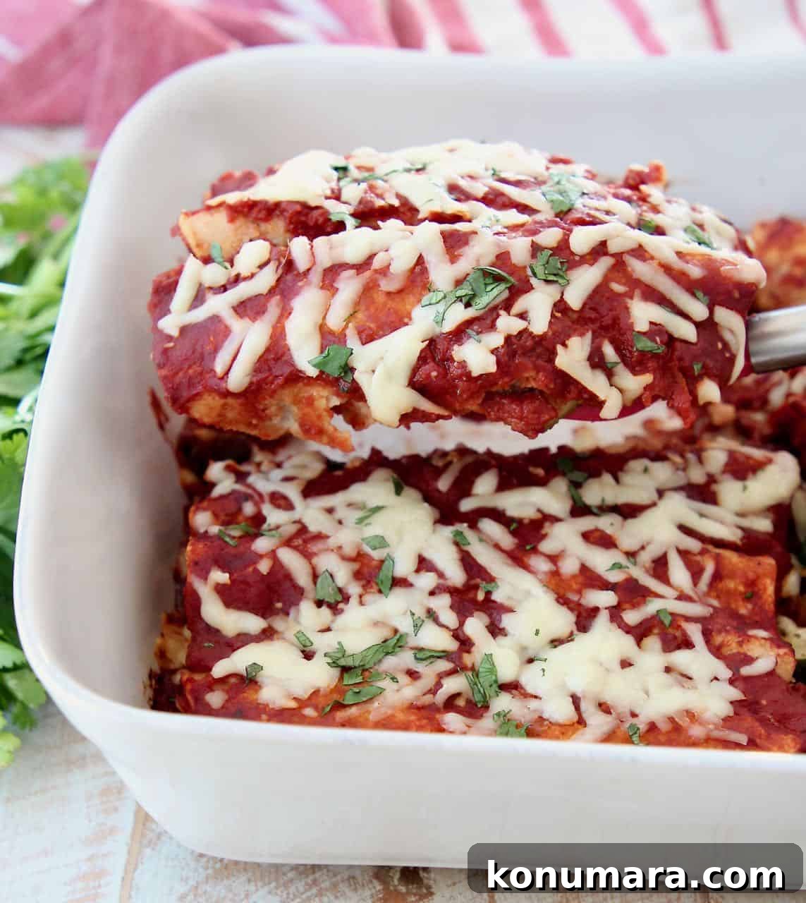 Enchiladas lifted out of casserole dish with spatula