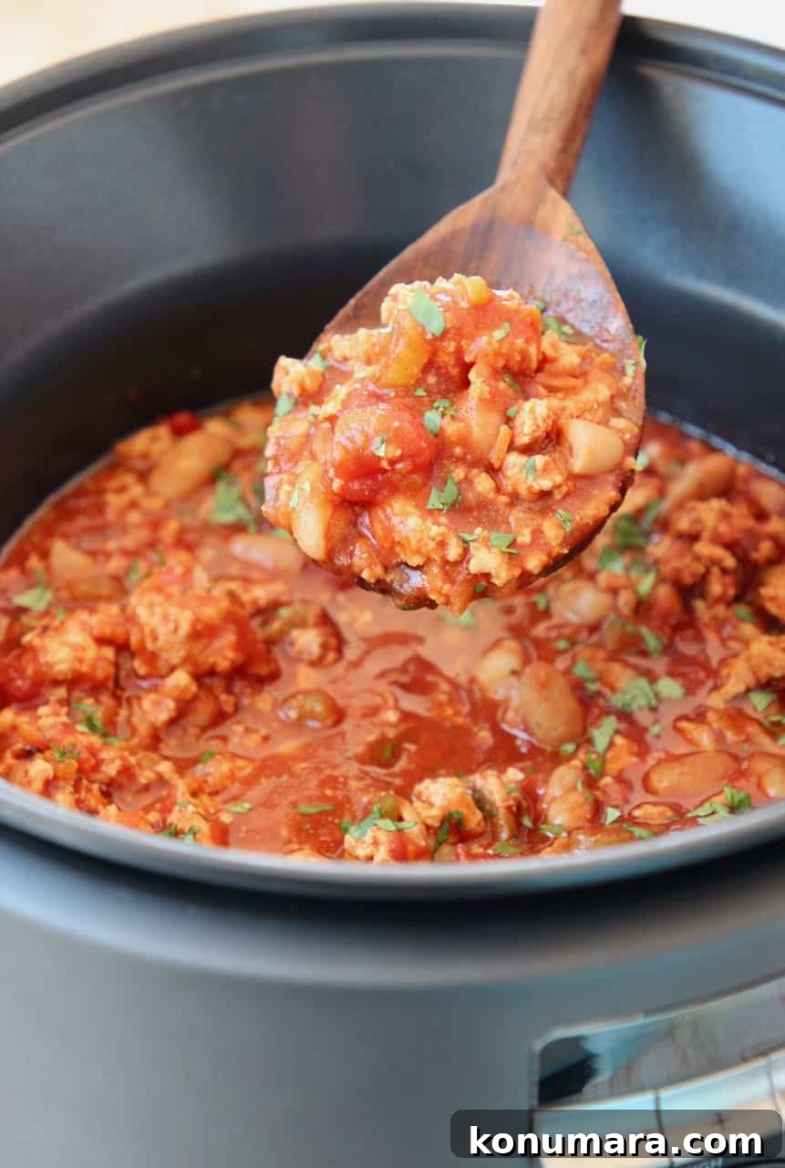 Slow Cooker Buffalo Chicken Chili Recipe 3 Buffalo chicken chili in a spoon coming out of a slow cooker